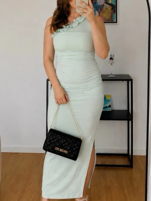 Oneshoulder klänning med volang - Snygg ljusgrön/ mint klänning med oneshoulder och volangdetalj vid axeln. 