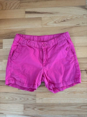 Rosa shorts från Ralph Lauren - Rosa shorts från Polarn o. Pyret. Shortsen har två sidofickor, en bakficka med knapp och stängs med knapp framtill. Perfekta för varma dagar och ger en färgstark touch till din outfit.