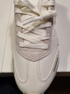 Fila, sneakers - Snygga vita sneakers från Fila med detaljer i ljusgrå mocka och mesh. Skorna har en chunky sula, vita skosnören och Fila-logga på sidan. Perfekta för dig som gillar en clean och modern stil.