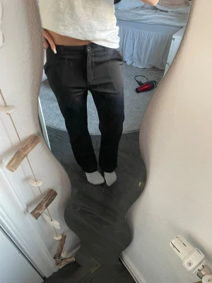 Svarta raka kostymbyxor - Snygga svarta kostymbyxor med rak passform och medel midja. Byxorna har knapp- och dragkedjestängning samt fickor fram. Perfekta för en clean och stilren look.