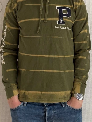 Polo Ralph Lauren hoodie - Polo Ralph Lauren hoodie med unik washed/bleached design och broderad logo fram. Bra skick utan större defekter. Säljes då den inte används längre.