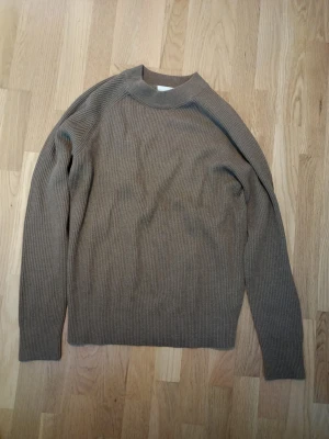 Brun ribbstickad tröja Jack & Jones - Ribbstickad tröja i brun nyans från Jack & Jones. Tröjan har högre krage och långa ärmar, tillverkad i mjukt stickat material. Enkel och stilren design som funkar till många olika looks.