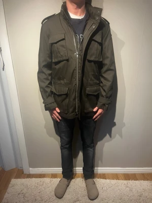Mörkgrön field jacket  - Mörkgrön fieldjacket från märket emilio. Storleken är M och modellen har vanligtvis S därför den ser så stor ut. Modellen är 175com och väger 62kg. Jackan är i nyskick och har använda fåtal gånger. Skriv för mer info