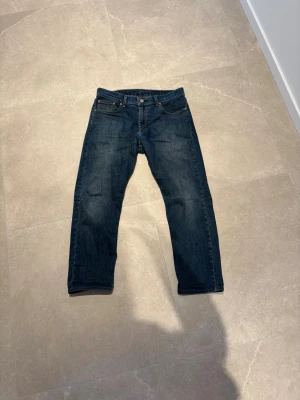 Mörkblå Levi's jeans straight fit - Klassiska mörkblå jeans från Levi's med rak passform och fem fickor. Jeansen har en snygg tvätt och ikonisk läderpatch bak i midjan. Perfekta för en avslappnad och tidlös stil.