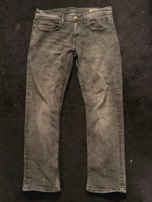 Grå straight baggy jeans med slitningar - Snygga grå jeans i straight baggy-modell med lätt slitna detaljer och klassisk femficksdesign. Jeansen har en något tvättad look och raka ben. Perfekta för en avslappnad och trendig stil.