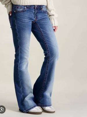 Blå bootcut jeans med brodyr - Säljer ett par blå bootcut jeans med röda broderade detaljer längs sidorna och på bakfickorna. Det är ett jätte litet hån vid bälteshällorna men man ser inte de så tydligt, jag är 164 och dom passar mig nästan helt i längden