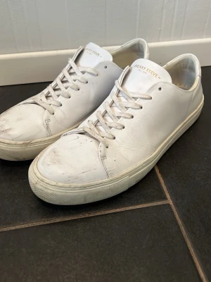 Vita Sneaky Steve lädersneakers - Stilrena vita sneakers från Sneaky Steve i äkta läder med klassisk låg profil och vita snören. Snygg minimalistisk design som passar till det mesta. Yttersulan är vit och har ett diskret mönster för bra grepp.