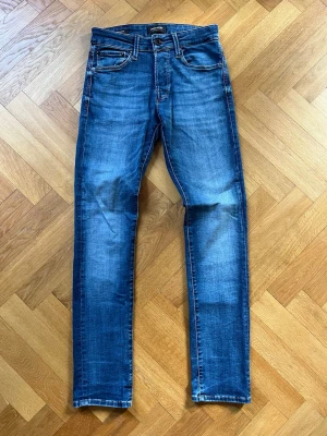 Blå Slim Glenn Jack & Jones jeans - Snygga blå slim fit jeans från Jack & Jones i modellen Slim Glenn. Jeansen har normal midja och raka ben och storleken W27 L30. Mycket gott skick.