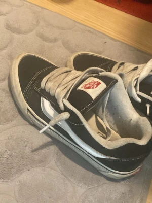 Svarta Vans Old Skool sneakers - Klassiska Vans Old Skool sneakers i svart canvas och mocka med vit sidorand och vita snören. Låg modell med vit gummisula och Vans-logga på plösen. Perfekta för en avslappnad streetstil.