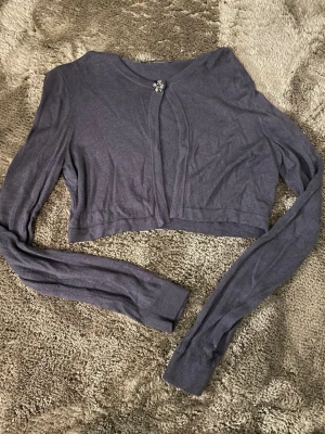 Lila cropped kofta från Sisley - Snygg lila cropped kofta från Sisley med lång ärm och dekorativ glittrig knapp framtill. Knappt använd💕