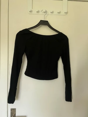 Svart långärmad croppad topp - En svart, långärmad croppad topp med djup rygg. Topp som passar till många outfits och tillfällen.