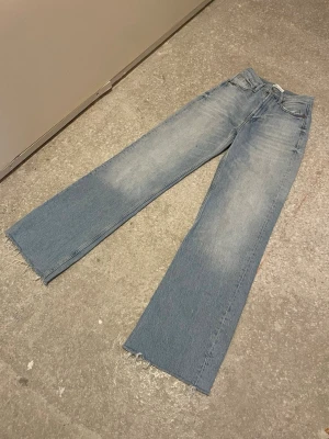 Blå wide jeans från Zara - Snygga ljusblå jeans från Zara med wide passform och råa, fransiga benslut. Klassisk femficksmodell i jeansmaterial med hög midja. Perfekta för en trendig och avslappnad look.