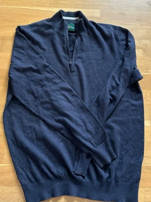 Mörkblå halvzip-tröja Alan Paine - Mörkblå stickad tröja från Alan Paine med halv dragkedja vid halsen. Tröjan har lång ärm, ribbade muddar och klassisk passform. Perfekt för lager-på-lager och snygg till jeans eller chinos. Ny pris: 1900kr