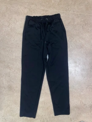 Svarta mjukisbyxor med dragsko - Säljer ett par svarta finbyxor. Byxorna har två sidofickor fram. Materialet är mjukt och bekvämt.