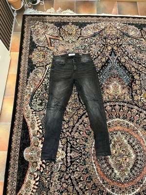 Svarta slim fit jeans från RS - Säljer ett par svarta slim fit jeans från RS med klassisk femficksmodell och dragkedjegylf. Jeansen har en lätt tvättad look och smal passform som sitter snyggt längs benen. Materialet är troligtvis bomull med lite stretch för extra komfort. Köpte från newyorker för 230kr