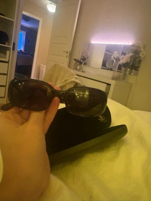 Bruna CHIMI solglasögon rektangulära - Snygga solglasögon från CHIMI med rektangulära bågar i brunmelerad plast. Glasen är mörka och bågarna har en diskret CHIMI-logga i guld på sidan. Perfekta för att lyfta din stil under soliga dagar.