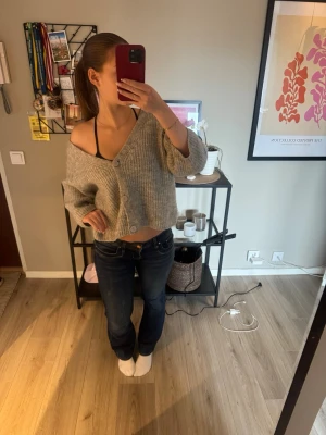 Grå cropped kofta med knappar - Mysig grå stickad kofta i cropped modell med stora knappar framtill. Koftan har en avslappnad passform och kan bäras off-shoulder för en trendig look. Perfekt att slänga över ett linne eller t-shirt för en chill outfit.