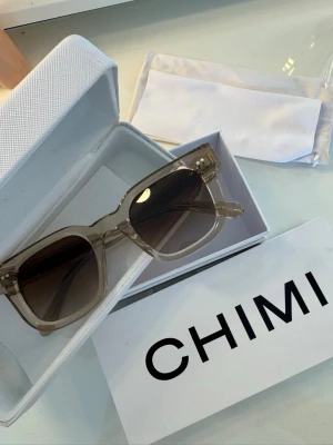 Solglasögon CHIMI - Snygga solglasögon från CHIMI med transparent beige båge och fyrkantig form. Glasen är mörka och ger en cool kontrast till den ljusa ramen. Kommer med originalfodral och putsduk. Perfekta för dig som vill ha en stilren accessoar. Pris kan diskuteras!