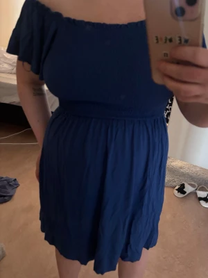 Blå off shoulder klänning - Säljer en blå off shoulder klänning med korta, vida ärmar. Klänningen är lätt utställd och materialet känns mjukt och luftigt, perfekt för sommaren. Klänningen har en enkel och stilren design som är lätt att matcha. 💙