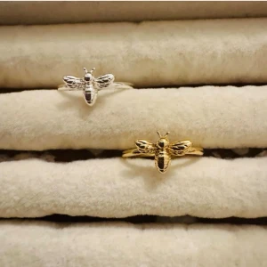 Styck pris  - Två ringar med detaljerade bidesign, en i guldfärg och en i silverfärg. Biet har tydliga vingar och kropp, vilket ger en cool och unik look. Perfekt för dig som gillar naturinspirerade accessoarer och vill sticka ut med ditt smycke.
