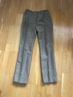 Beige linnebyxor från Betty Barclay - Snygga beige linnebyxor från Betty Barclay Collection. Byxorna har raka ben, pressveck och hällor för skärp. Tillverkade i ett luftigt linnetyg som passar perfekt till varmare dagar. Klassisk och stilren design som är lätt att matcha.