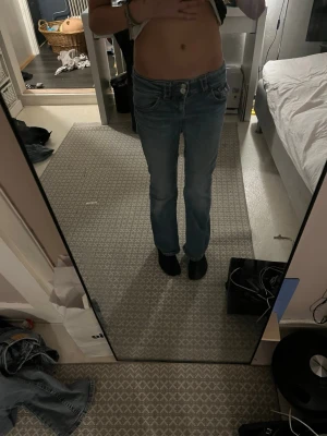 Blå bootcut jeans med låg midja - Säljer ett par blå bootcut jeans med låg midja och klassisk femficksdesign. Jeansen har en lätt tvättad look och raka ben som går ut lite nedtill. Perfekta för dig som gillar en avslappnad och trendig stil.