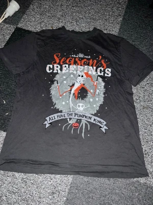 Nightmare Before Christmas T-shirt - Säljer en svart T-shirt från Disney med motiv från The Nightmare Before Christmas. Trycket har texten 'Season's Creepings' och 'All Hail The Pumpkin King' med Jack Skellington i centrum. T-shirten är kortärmad och gjord i mjuk bomull. Skön baggy tröja