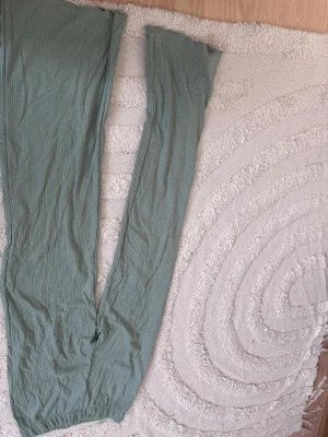 Ribbade gröna leggings - Säljer ett par ribbade leggings i en mjuk, ljusgrön. Perfekta för en chill och avslappnad stil. Materialet känns stretchigt och följsamt. Vet ej varför bilderna är upp och ned. Ord pris 350kr