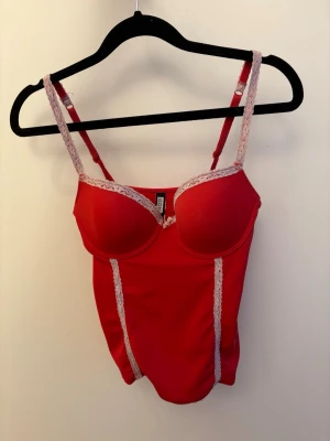Snygg korsett topp med vit lace  - Super skönt röd topp med inbyggd bh, som vita spets detaljer, endast använd en gång och är därför i väldigt bra skick ❤️skriv om ni har frågor (skulle säga den passar typ C kupa) 🥰väldigt stretchig så passar nog dem flesta!