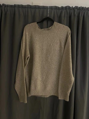 Beige stickad tröja med rund hals - En enkel och stilren beige stickad tröja med rund halsringning och långa ärmar. Tröjan har ribbade muddar vid ärmslut och nederkant. Perfekt för lager på lager och passar till det mesta i garderoben.