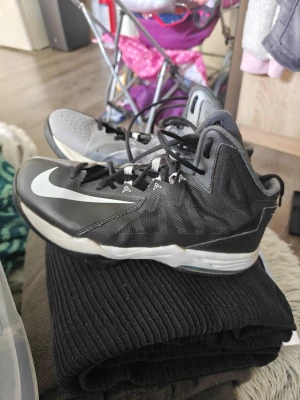 Nike svart/grå höga sneakers - Säljer ett par höga sneakers från Nike i svart och grått med vit swoosh på sidan. Skorna har snörning och en sportig design med ventilerande mesh och syntetmaterial. Perfekta för dig som gillar en cool och aktiv stil. BJ1 med rean på helgen 