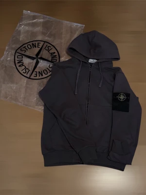 Tröja - En Stone Island hoodie med dragkedja, i mycket fint skick. Medföljer gör även en extra svart Stone Island badge. Den är liten i storlek, så jag rekommenderar den för dig som bär storlek S. Skickar inom 24 timmar🚚 Vid frågor eller önskemål om fler bilder var vänlig och kontakta.
