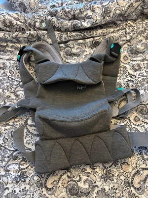 Grå bärsele från Najell Easy - Säljer en grå bärsele från Najell med vadderade axelband och midjebälte. Selen har flera justerbara remmar och spännen samt en mjuk, ergonomisk design i textilmaterial. Passar för att bära barn på ett bekvämt och säkert sätt.