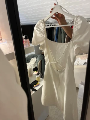 Vit kort puffärmad klänning - Säljer en vit kort klänning med puffärmar och snygg snörningsdetalj i ryggen. 💕