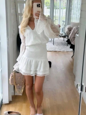 Vit klänning - Supersöt trendig vit kort klänning med smockad midja och spetsärmar. Perfekt till student eller till sommaren!!🤍🤍 Jättebra skick! Säljs då jag har en annan till studenten. 