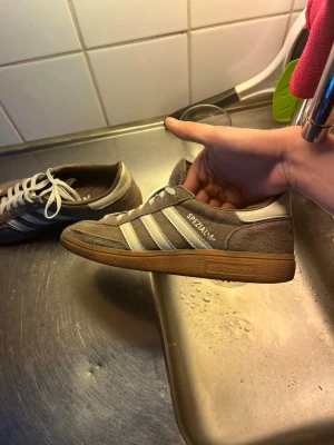 Adidas Spezial bruna sneakers - Säljer ett par Adidas Spezial sneakers i ljusbrun mocka med vita detaljer och klassiska tre ränder på sidan. Skorna har en brun gummisula och vita skosnören. Skorna är använda max 15 gånger. Finns inga defekter på användning. Skriv vid frågor!!!!