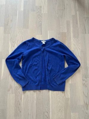 Kofta med knappar - Blå kofta från H&M som är perfekt för våren! 100% bomull. Det finns en extra knapp