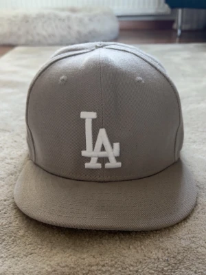 New eras keps LA dodgers - Säljer en stilren grå LA Dodgers keps från New Era med broderad vit LA-logga framtill och 1988 World Series-märke på sidan. Säljer billigt då den var för liten för mig. 