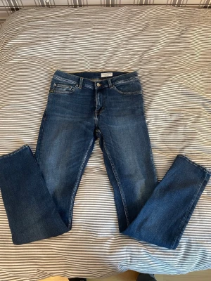 Tiger of Sweden slim fit-jeans - Säljer ett par klassiska mörkblå jeans från Tiger of Sweden. Jeansen har rak passform, fem fickor och snygga kontrastsömmar. Tillverkade i slitstarkt denim med en tidlös look och läderpatch bak i midjan.