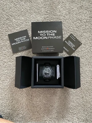 Omega x Swatch MoonSwatch svart klocka - Säljer en Omega x Swatch MoonSwatch Mission to the Moonphase. Klockan är svart med vit urtavla och detaljer, har tachymeter och flera subdials. Tillverkad i biokeramik och kommer i originalbox med manualer. Riktigt snygg och ikonisk modell! 