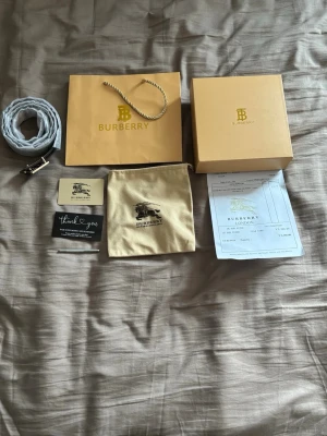 Burberry randigt bälte med logga - Snyggt bälte från Burberry med klassiskt randigt mönster i beige, grått och rött. 