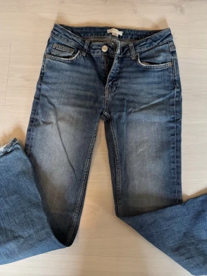 Blå jeans från Gina Tricot - Säljer ett par klassiska blå jeans från Gina Tricot i storlek 152. Jeansen har fem fickor, normal midja och raka ben. Snygg tvätt med lätt slitning och sköna att bära till vardags. Perfekta till en avslappnad stil!