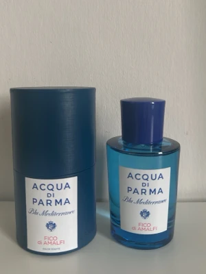 Acqua di Parma Fico di Amalfi parfym - Fräsch parfym från Acqua di Parma, Blu Mediterraneo Fico di Amalfi. Flaskan är cylinderformad i blått glas med matchande blått lock och vit etikett. Kommer med originalförpackning i samma blå färg och elegant design.