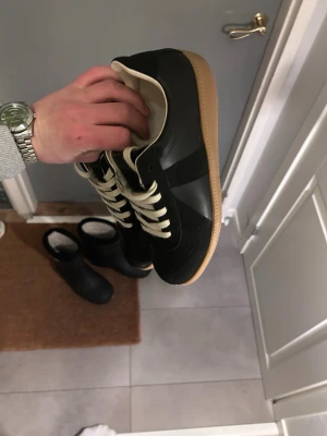 Maison margiela sneakers storlek 43 - Säljer ett par maison margiela sneakers i storlek 43 som jag bara använt ett par gånger och säljer för att dom inte passade mig. Kvitto finns. Skorna har en klassisk låg profil och är tillverkade i en mix av läder och mocka för en snygg kontrast. Perfekta för dig som gillar minimalistisk och tidlös design.