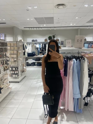 Svart axelbandslös långklänning - Säljer en svart, axelbandslös långklänning med figurnära passform. Klänningen är enkel och stilren, perfekt för dig som gillar minimalistisk stil. Tillverkad i mjukt material som sitter skönt mot kroppen.