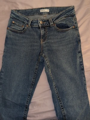 Blå bootcut jeans med detalj på bakfickan  - Super fina jeans för Gina, som aldrig är använda. Kan se små ut på bild men de är super stretchiga och är i storlek M 