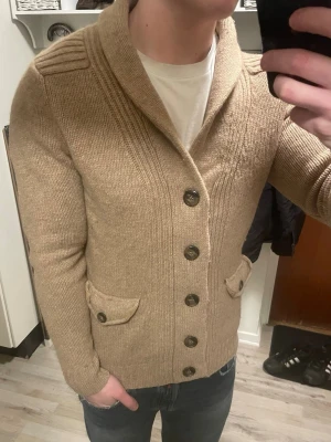 Brun stickad cardigan  - Otroligt snygg brun/beige stickad cardigan. Passar perfekt till kallare väder. Modellen är 180cm, 74kg. Priset kan såklart diskuteras!