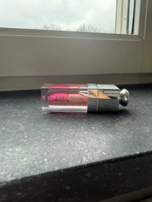 Dior Lip Glow Oil PINK - Säljer en Dior Lip Glow Oil i färgen 001 PINK. Läppoljan kommer i en genomskinlig fyrkantig tub med silverfärgat lock och applikator. Oljan har en fräsch rosa nyans och ger glansig finish. Perfekt för dig som vill ha återfuktade och glansiga läppar med en hint av färg.