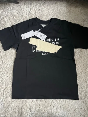 Svart Maison Margiela t-shirt - En maison margiela t shirt som är i nyskick, qr kod fungerar. Storlek S men den är stor i storleken så den passar nog M också. Hör av er vid frågor eller funderingar! 