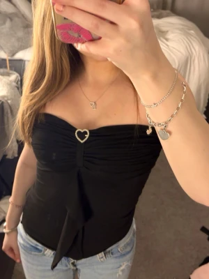 Svart axelbandslös tubtopp med hjärtdetalj - Snygg svart axelbandslös tubtopp, pris kan alltid diskuteras💕